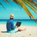 man with laptop on tropical sand beach, remote work concept