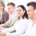 Five business people sitting in a row and writing notes on a business training. Selective focus placed on businessman in front. Browse my portfolio for vertical version.