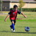 A boy runs a soccer ball across a grassy field