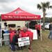 Walter and Sandra Reaves and their young son pose in front of an i9 Sports tent whose awning reads, "The Way Youth Sports Should Be"