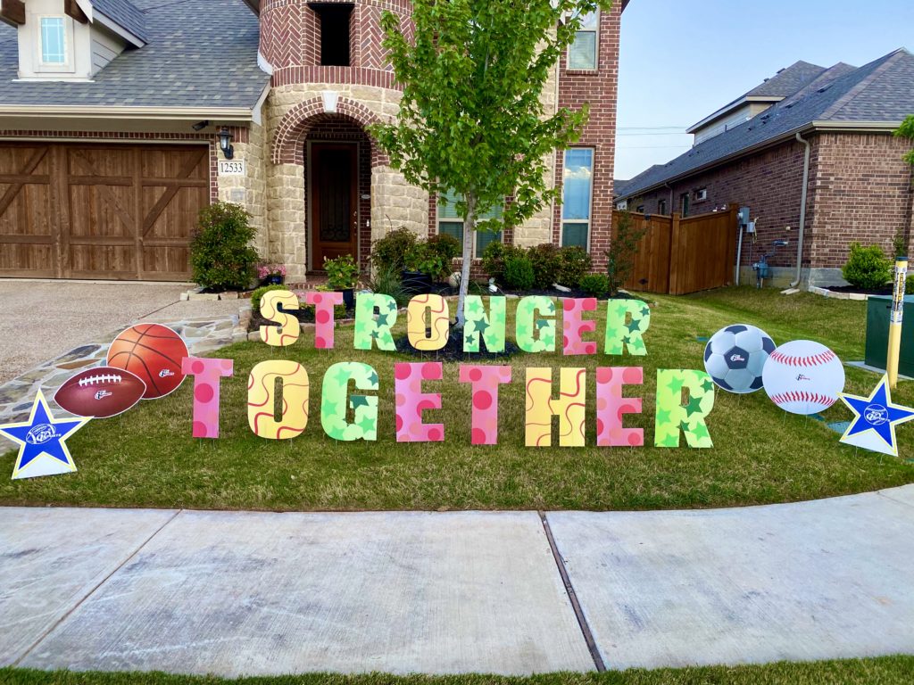 Colorful letters posted in a front yard spell out “Stronger Together.”