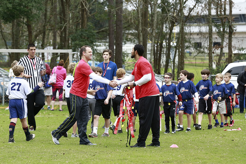 i9 Sports coaches shake hands while their teams exchange "good game" hand slaps after a soccer game.