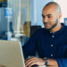 Man at desk uses his laptop.