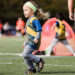 A small girl chases a soccer ball.