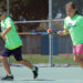 For a tennis drill, a boy and a girl run while balancing a tennis ball on their racquets.