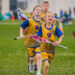 Kids holding their lacrosse sticks walk across a playing field. The number of sports we offer makes i9 Sports one of the best low cost franchises.