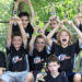 i9 Sports players in a youth sports league cheer as they hold up their awards.