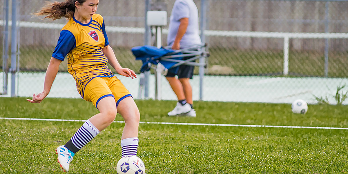 A girl kicks a soccer ball.