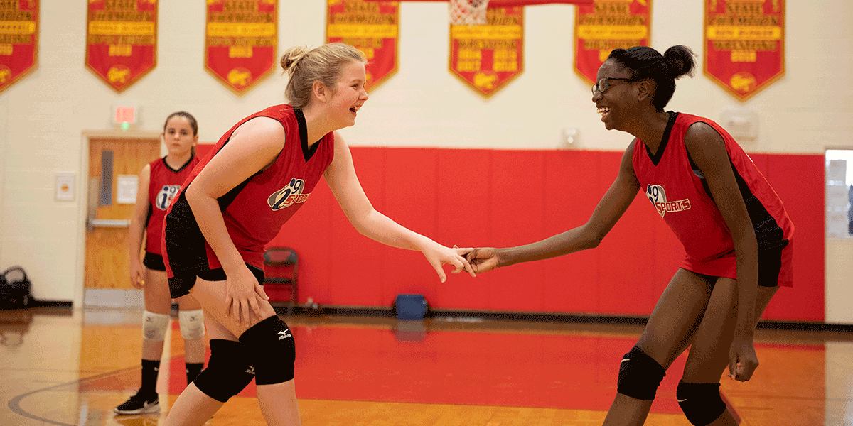 Girls are laughing while standing on the basketball court.