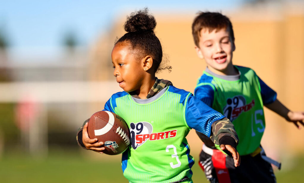 A boy and a girl play flag football.